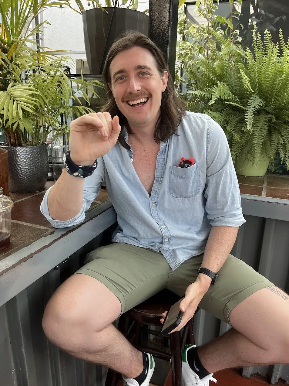 Nick smiling and waving at a garden cafe